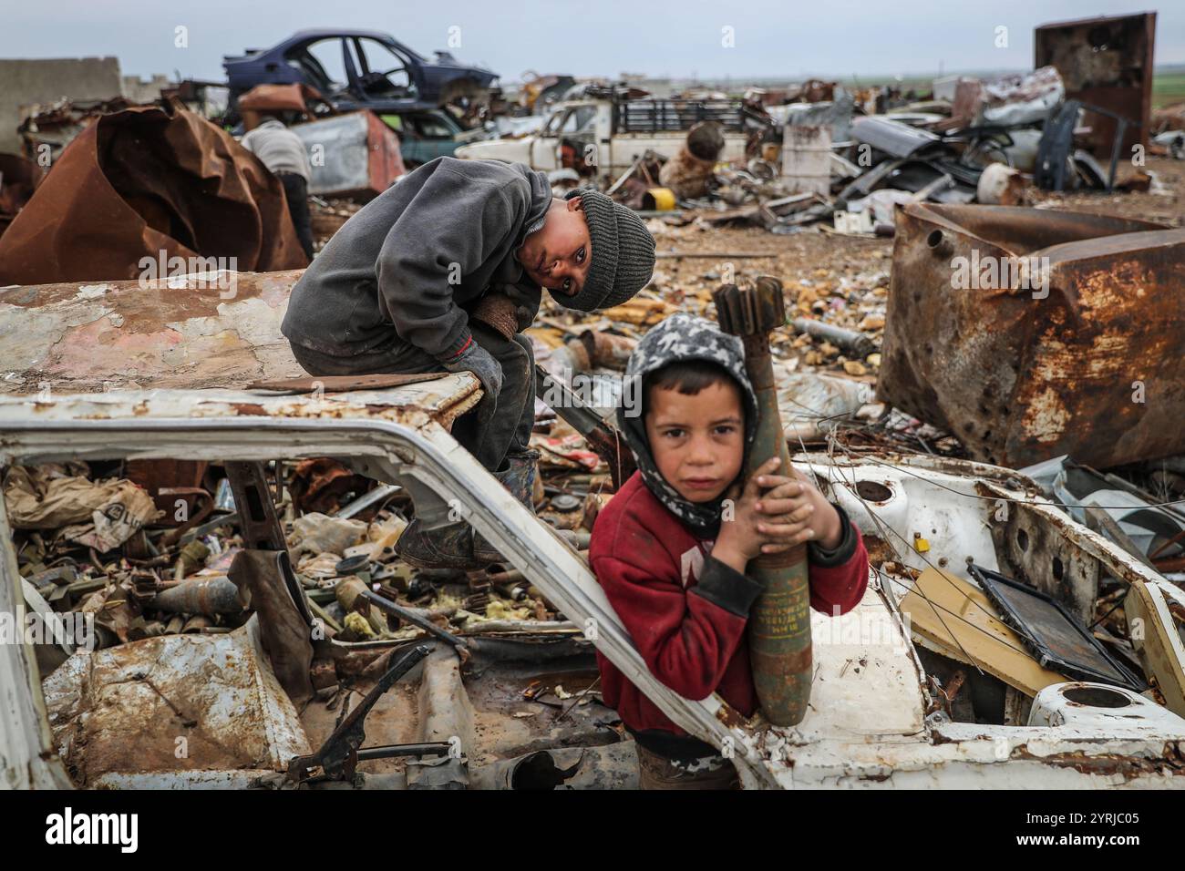 Idlib, Siria. 2 marzo 2021. Abdel Karim Hassan (r), di 7 anni, ha un proiettile di mortaio inesploso e si siede accanto a Malik Junaid di 9 anni su un'auto cannibalizzata in una discarica per munizioni e resti di artiglieria gestiti dalla famiglia Junaid. Il fotografo del dpa Anas Alkharboutli è stato ucciso durante i rinnovati combattimenti in Siria. Crediti: Anas Alkharboutli/dpa/Alamy Live News Foto Stock