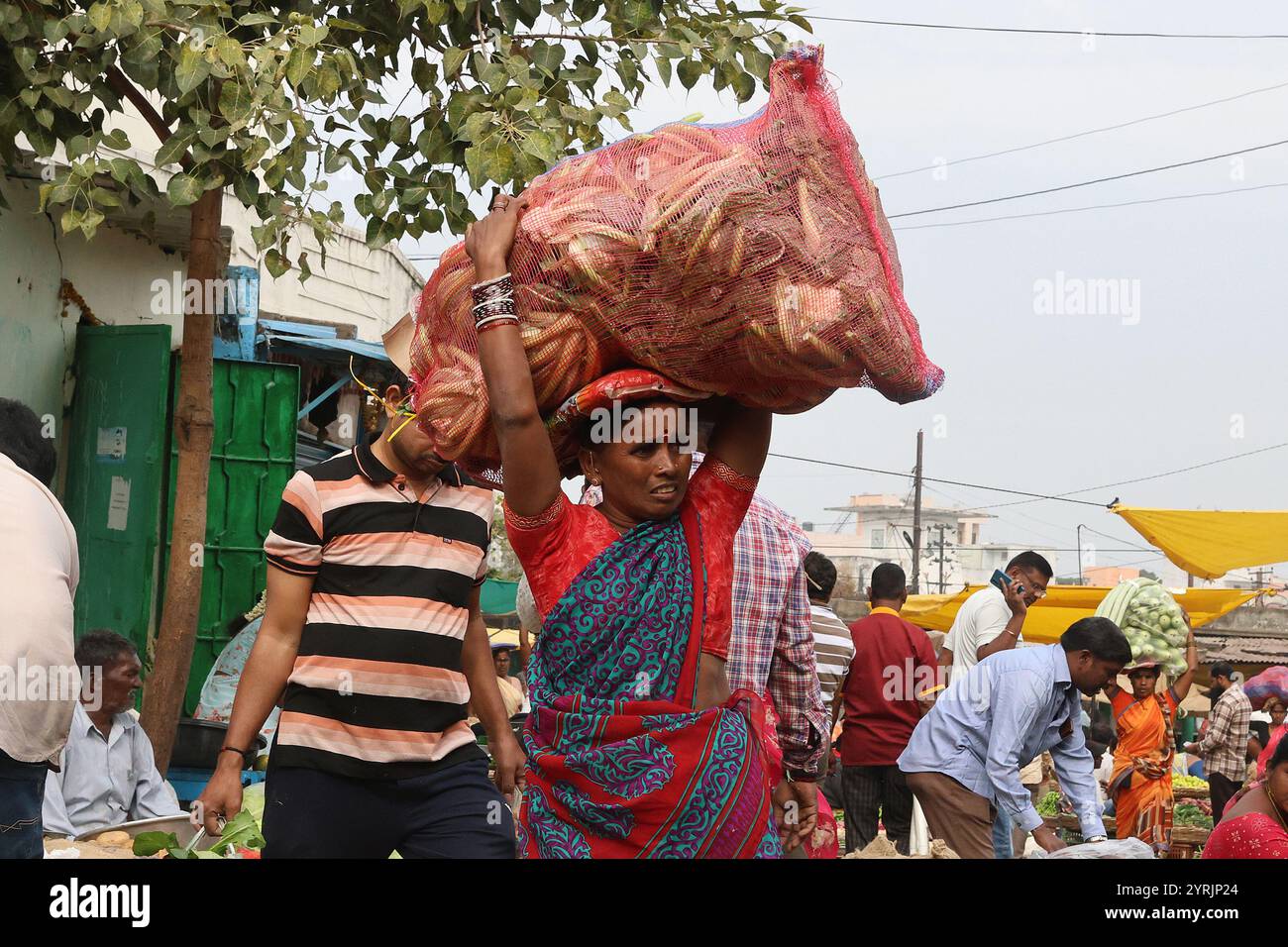 Una lavoratrice donna porta un sacco di verdure sulla testa nel mercato di Secunderabad, Telegana, India Foto Stock