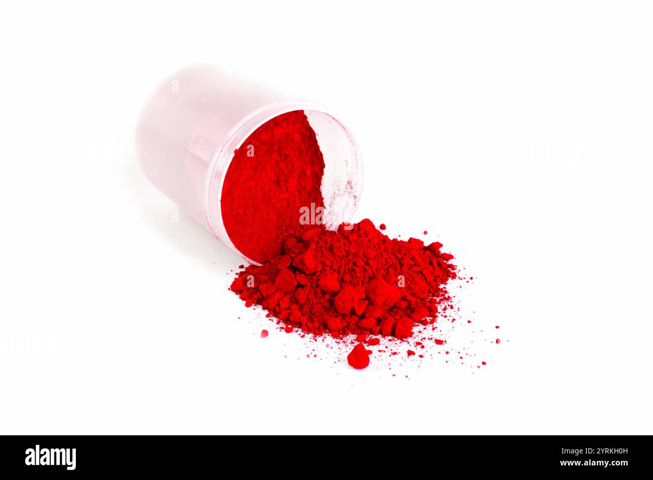 La polvere rossa brillante fuoriesce da un contenitore su una superficie bianca durante la lavorazione Foto Stock