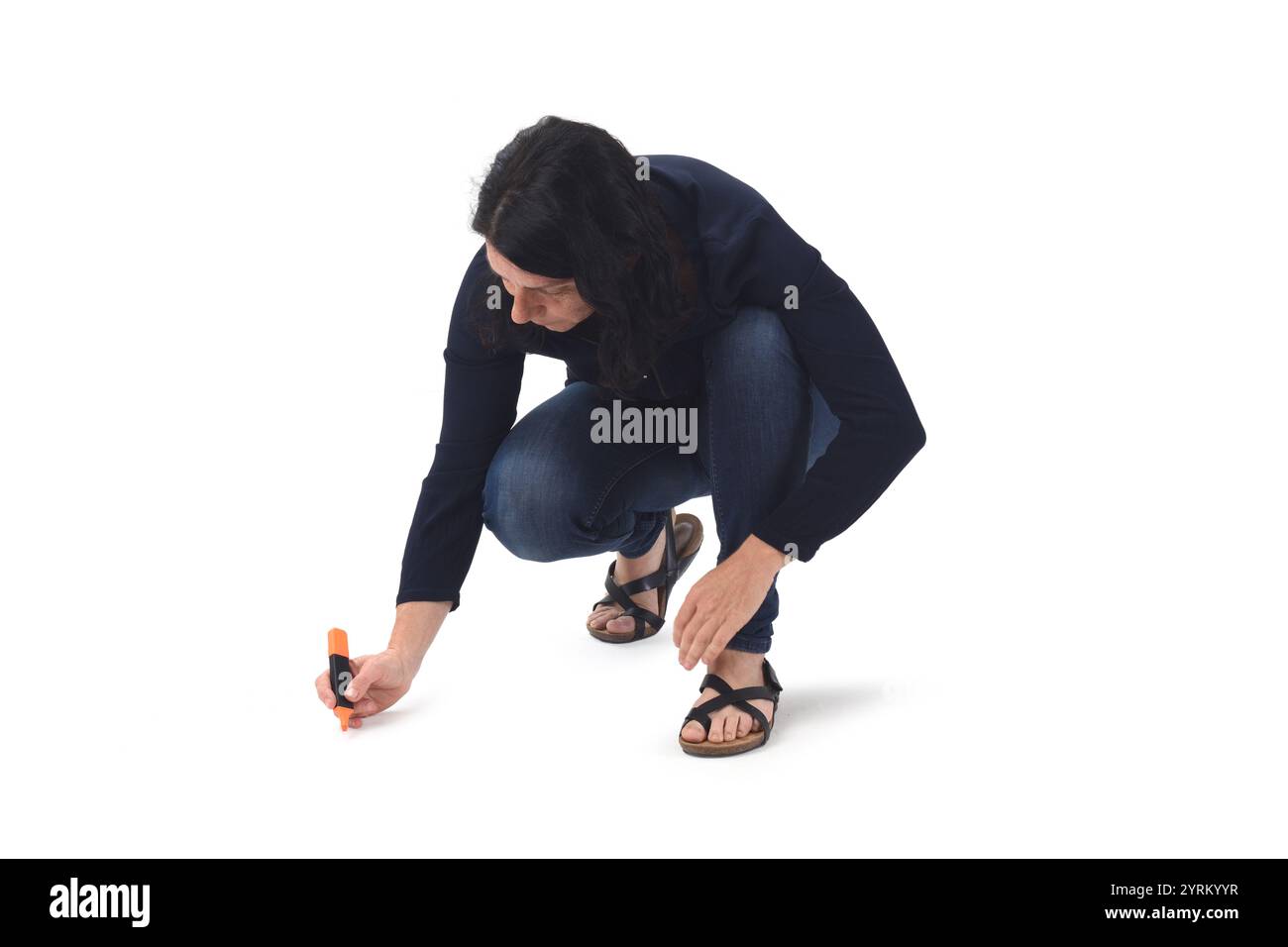 vista frontale di una donna che disegna o scrive sul pavimento con un pennarello su sfondo bianco. Foto Stock