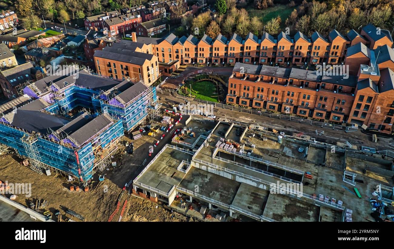 Vista aerea di un cantiere residenziale. Le case a schiera in mattoni sono complete, mentre gli edifici adiacenti sono in costruzione, circondati da impalcature Foto Stock