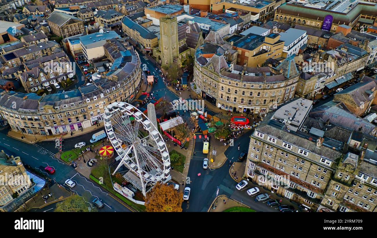 Vista aerea di una piazza della città con una ruota panoramica, bancarelle del mercatino di Natale ed edifici in pietra. Strade e auto sono visibili. La scena è predominante Foto Stock