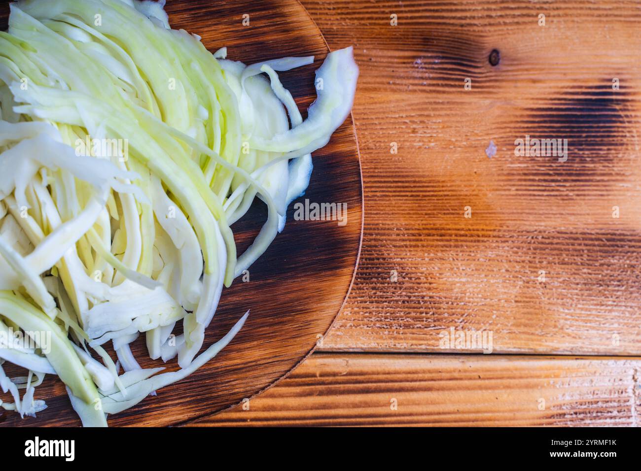 Cavolo bianco tagliato a strisce su un asse di legno con un coltello. Foto di alta qualità Foto Stock