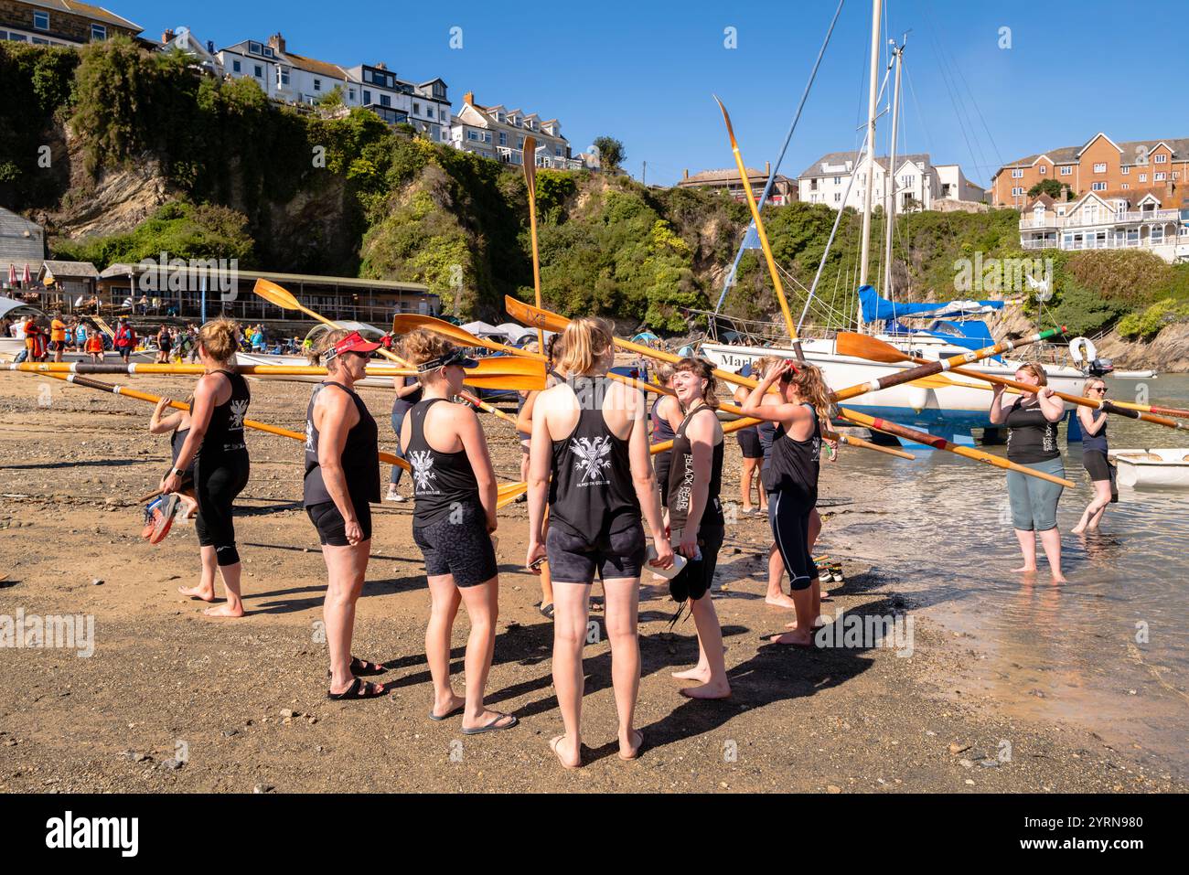 La Pilot Gig Crew del Falmouth Gig Club trasporta i remi in attesa di salire a bordo dei loro Pilot Gigs per i Campionati femminili della contea di Newquay Foto Stock