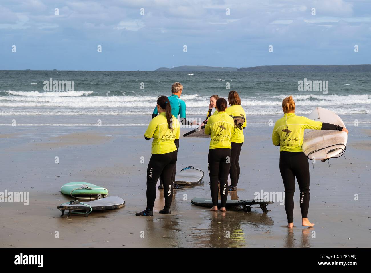 Un istruttore di surf della Escape Surfing School tiene una lezione di surf con un gruppo di studentesse a Towan Beach a Newquay in Cornovaglia nel Regno Unito. Foto Stock