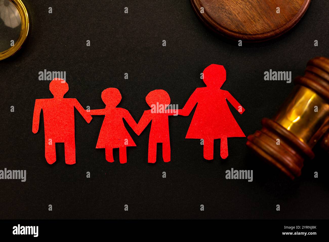 Personaggi della famiglia in carta rossa, martelletto e lente d'ingrandimento su sfondo nero. Custodia dei figli, adozione, divorzio e concetto di supporto legale. Foto Stock