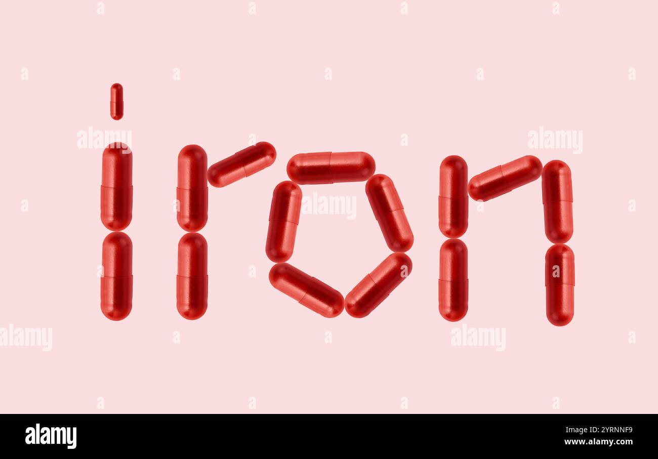 Idea creativa per il concetto di anemia da ferro. Supplemento di ferritina in capsula rossa. Parola con capsula che rappresenta l'integrazione di ferro per il trattamento del ferro An Foto Stock