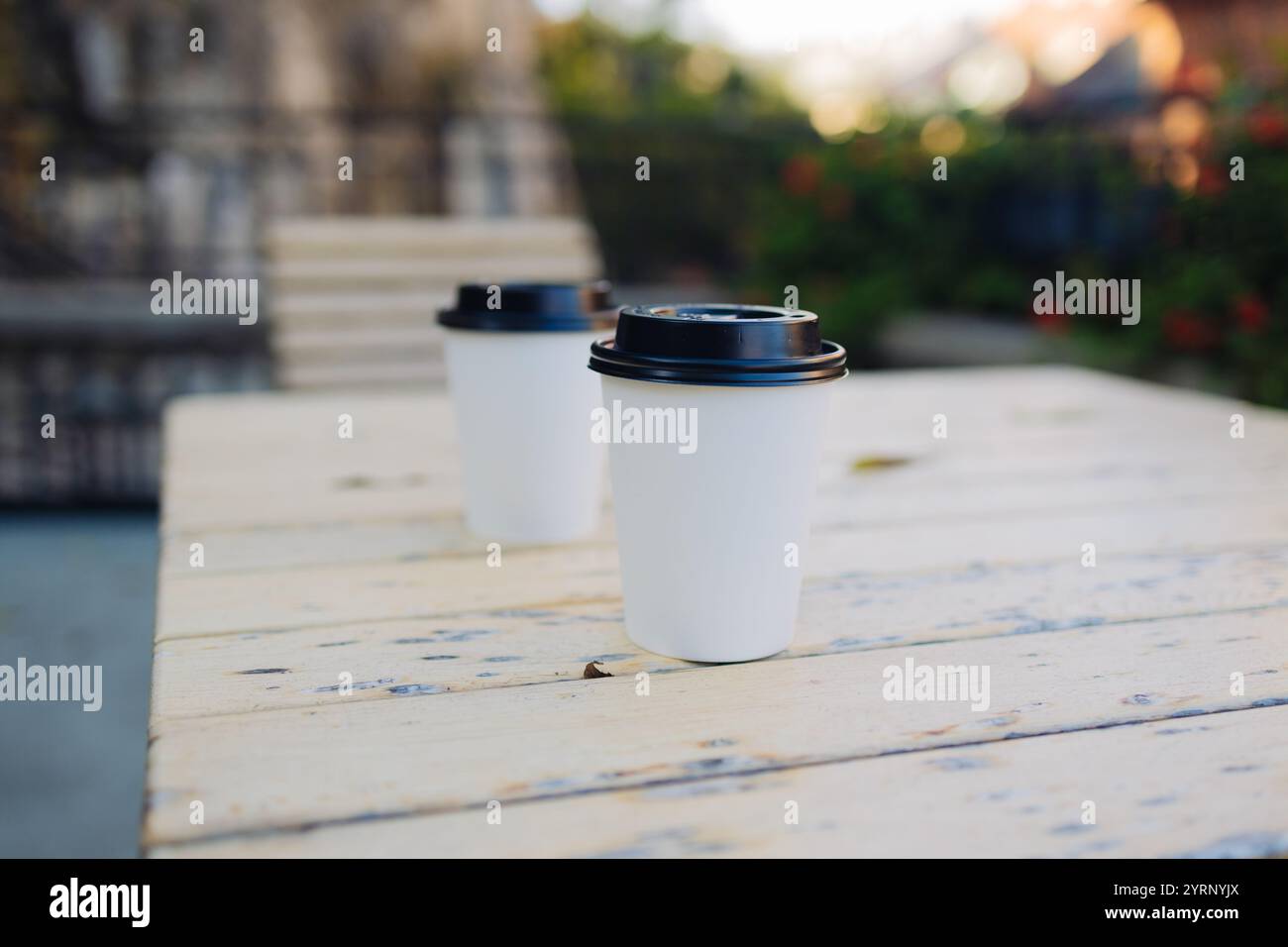 Tazza da caffè da asporto in cartone con coperchio in plastica su un tavolo in legno all'aperto Foto Stock