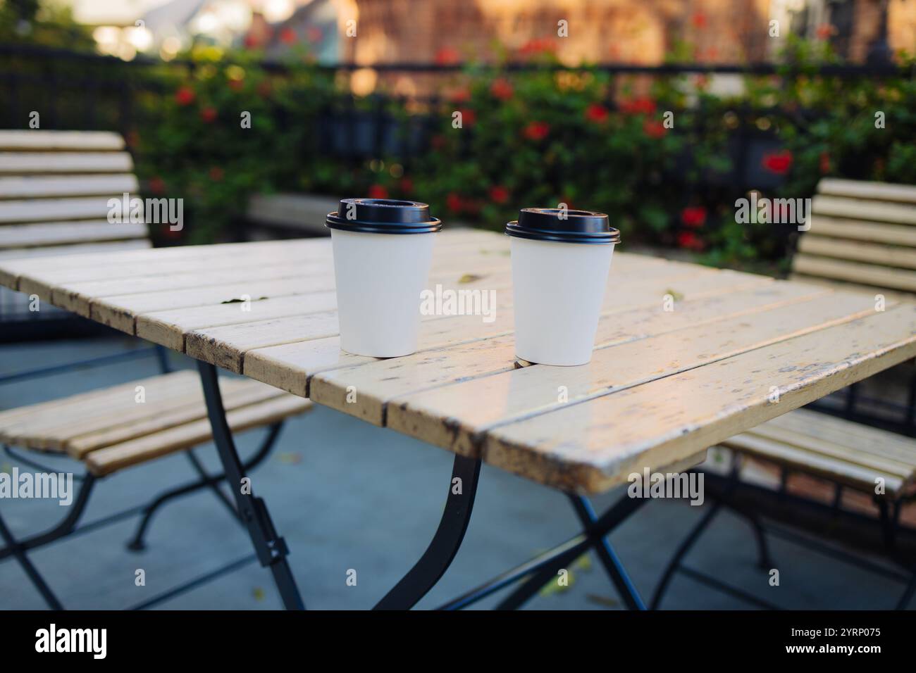 Tazza da caffè da asporto in cartone con coperchio in plastica su un tavolo in legno all'aperto Foto Stock
