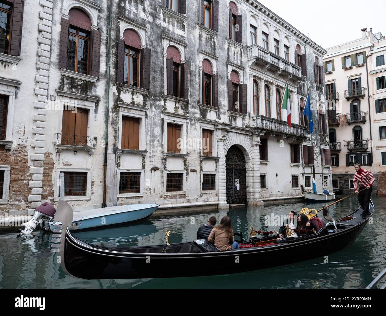 I turisti in giro in gondola lungo un canale d'acqua per le strade di Venezia, Italia Foto Stock