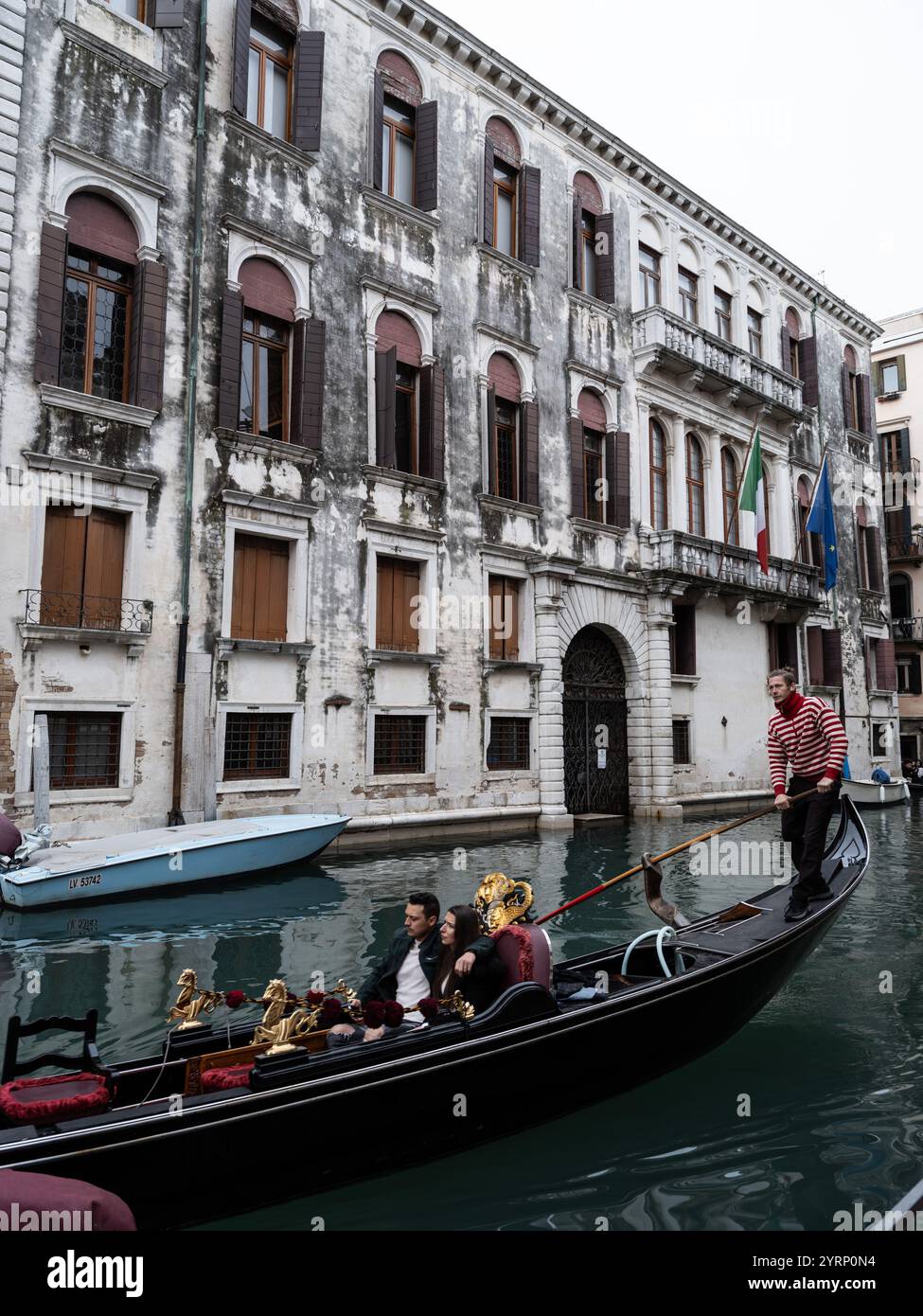 I turisti in giro in gondola lungo un canale d'acqua per le strade di Venezia, Italia Foto Stock