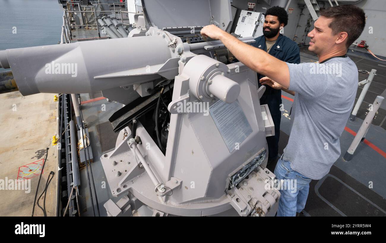 USS Comstock (LSD 45) Gunner's Mate 1st Class Petty Officer Isiah Johnson (a sinistra) e James Holle, MK 38 in-Service Engineering Agent con Naval Surface Warfare Center (NSWC) Indian Head Division's Picatinny Detachment in New Jersey, reinstallano l'alimentatore di una delle mitragliatrici MK 38 a bordo dell'LSD 45 durante uno sposo navale presso la NSWC Port Hueneme Division in California il 3 giugno 2024. Il gruppo di alimentazione viene rimosso regolarmente per l'ispezione e la manutenzione per garantire la prontezza operativa. (Foto della Marina degli Stati Uniti di Eric Parsons/pubblicato) Foto Stock