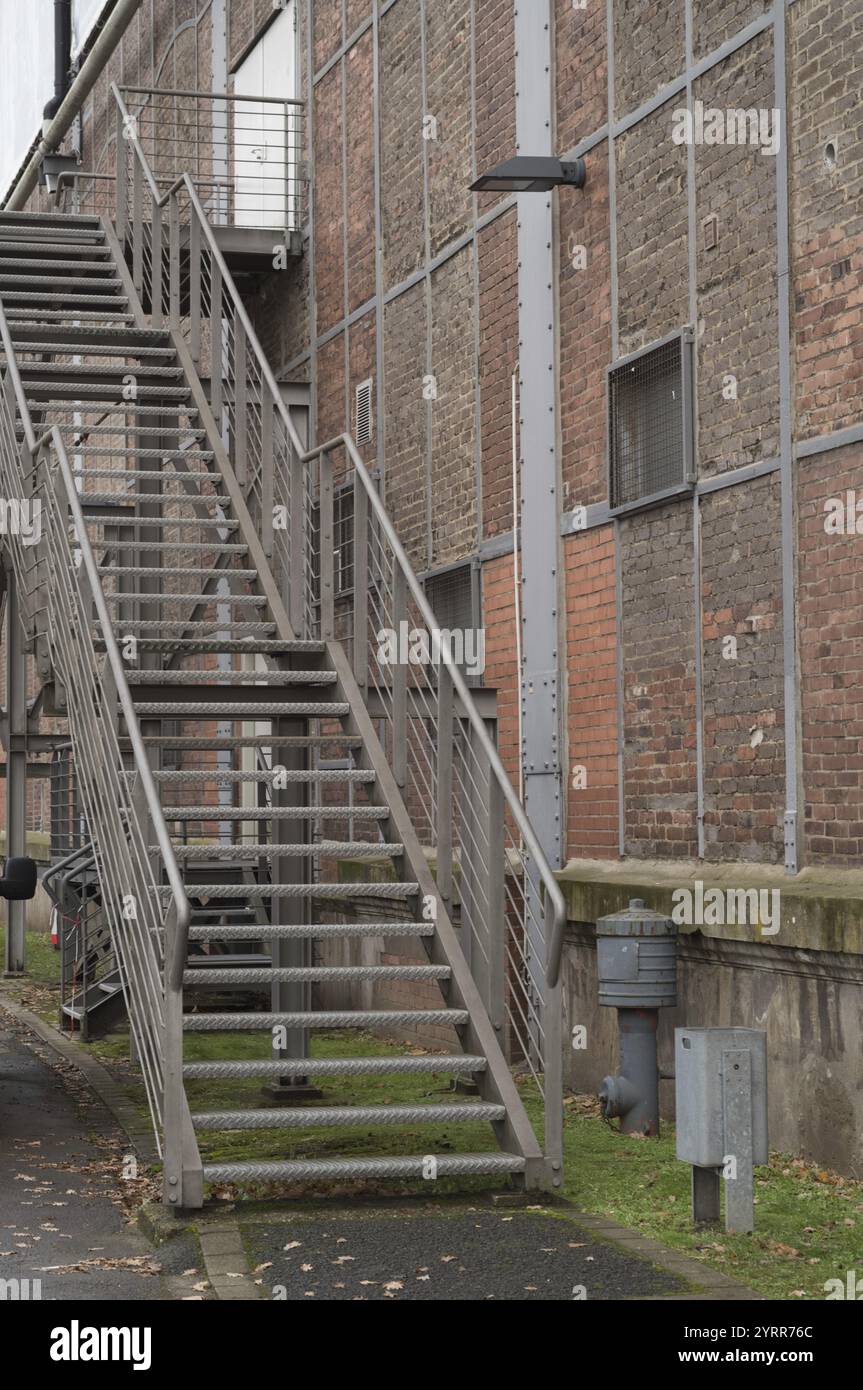 La scala esterna in metallo fornisce accesso ad un edificio industriale con una facciata in mattoni Foto Stock