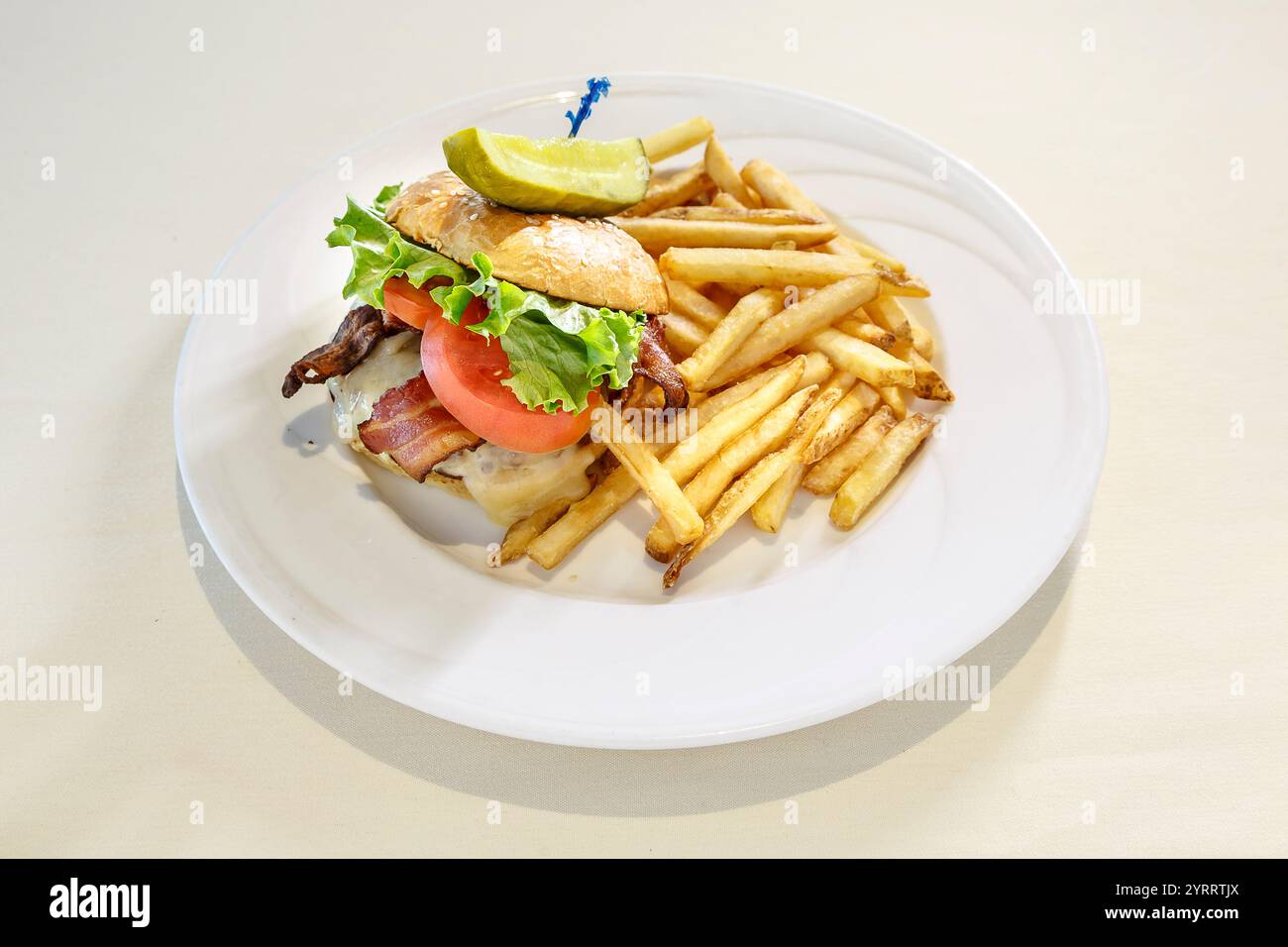 Un piatto di panino e patatine fritte. Il panino è un panino con pancetta e pomodoro. Le patatine fritte vengono tagliate a metà e si trovano sul lato della piastra Foto Stock