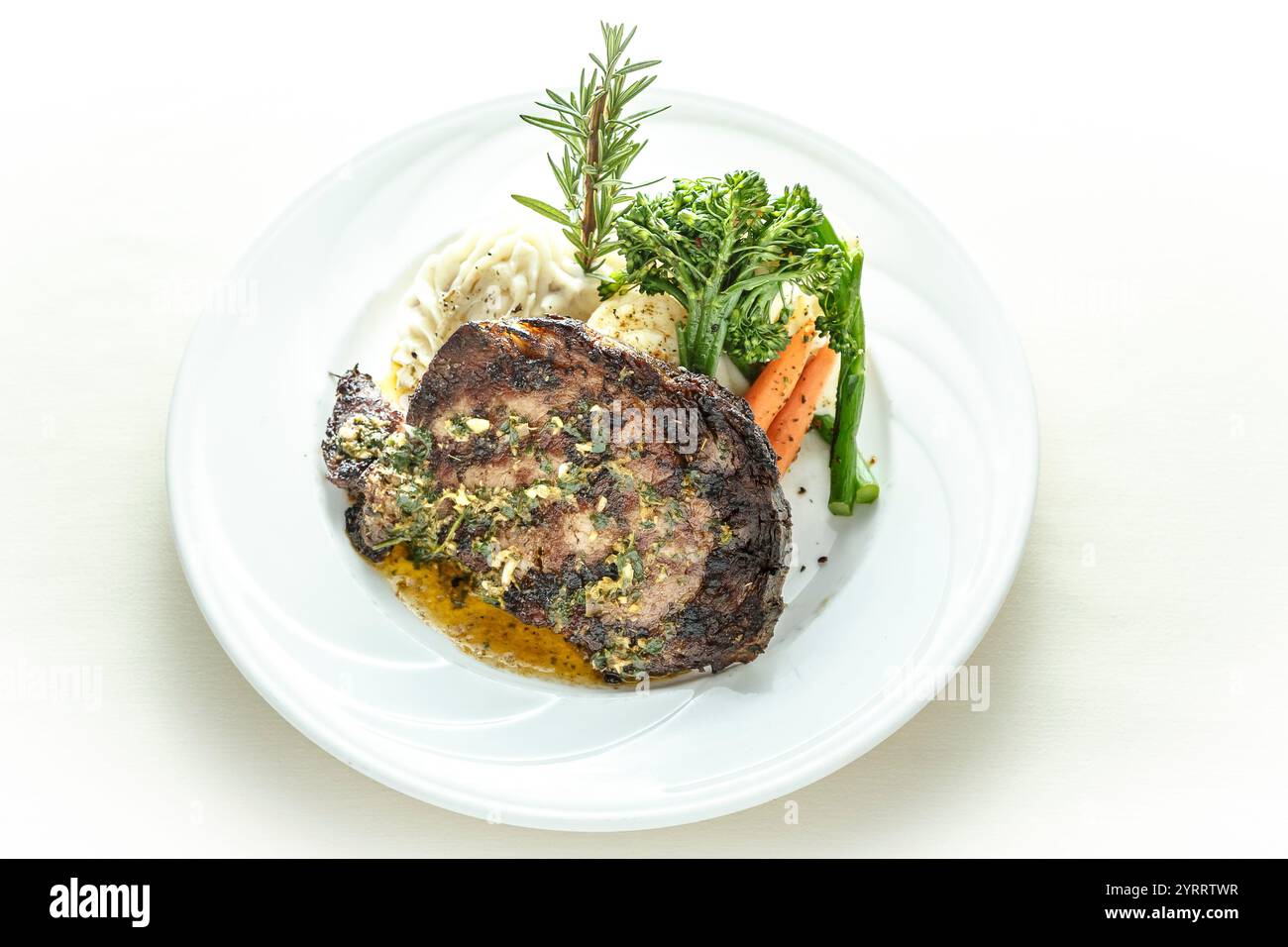Un piatto di cibo con un pezzo di carne e verdure. La carne è cotta e ha sopra una salsa. Le verdure sono carote e broccoli. La piastra è W Foto Stock