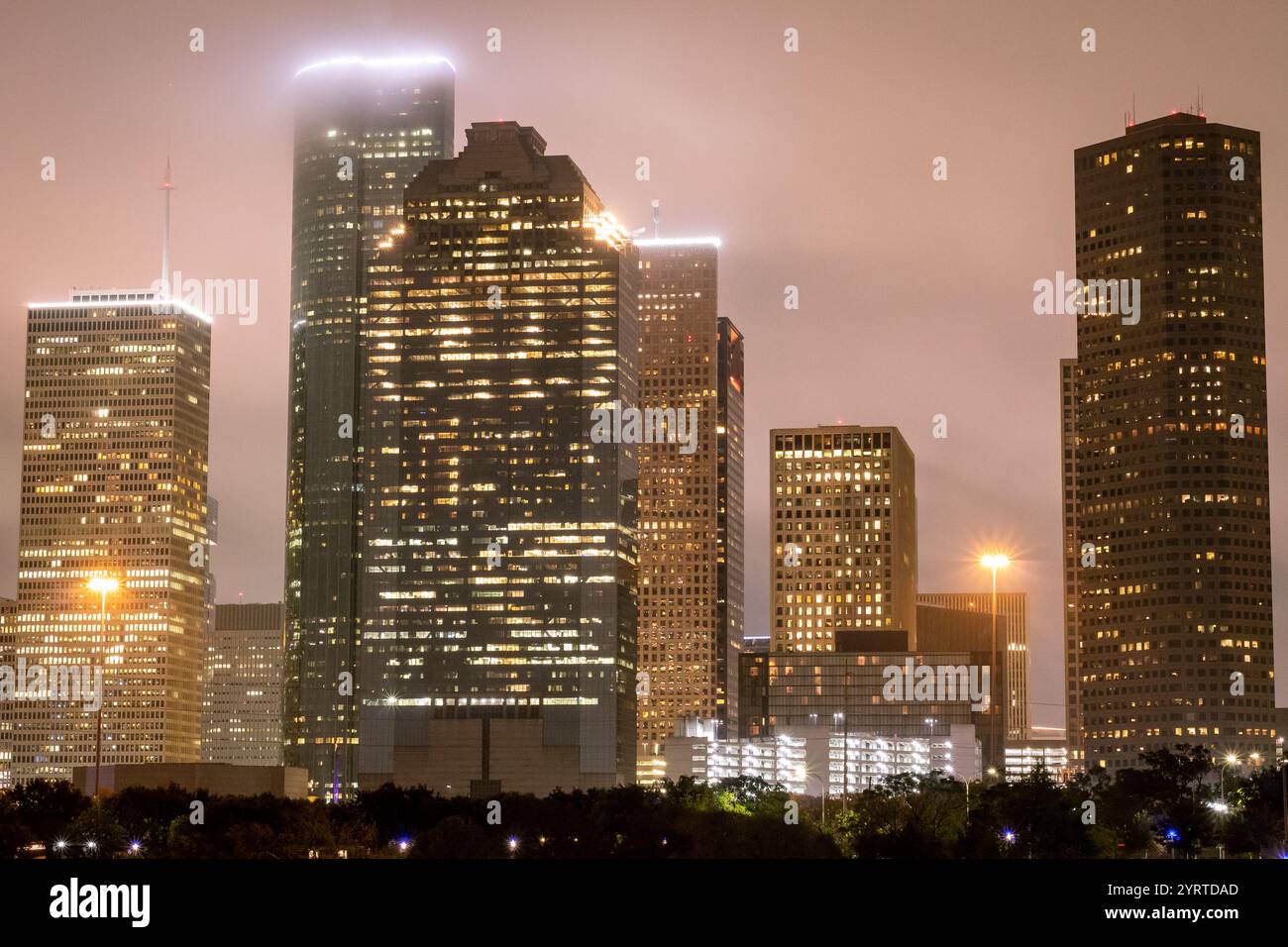 Edifici illuminati dello skyline del centro di Houston, Texas. Foto scattata in una serata nebbiosa e nuvolosa Foto Stock