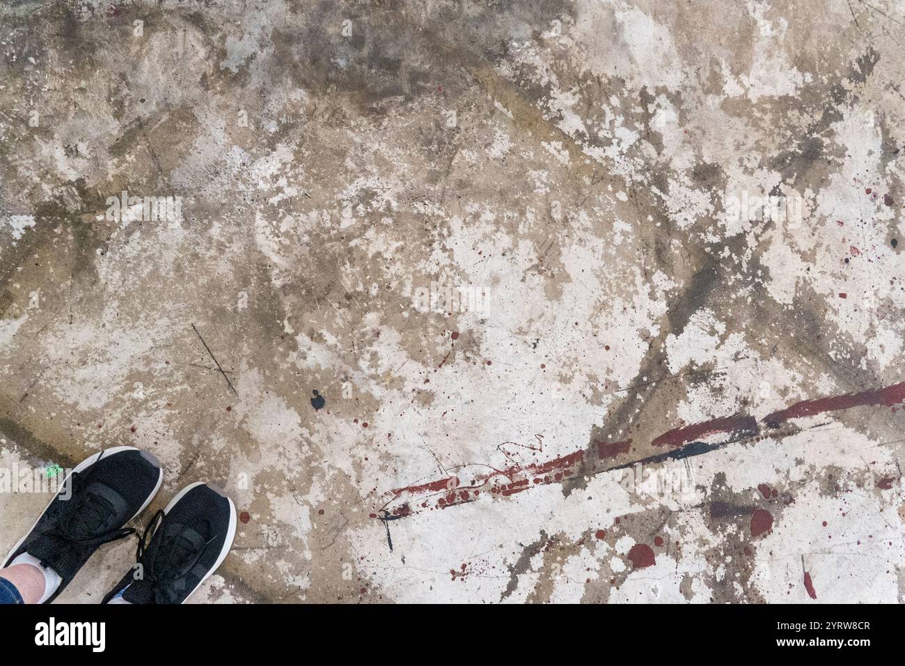 Pavimento in calcestruzzo con stampe di scarpe e macchie in un ambiente industriale durante il giorno Foto Stock