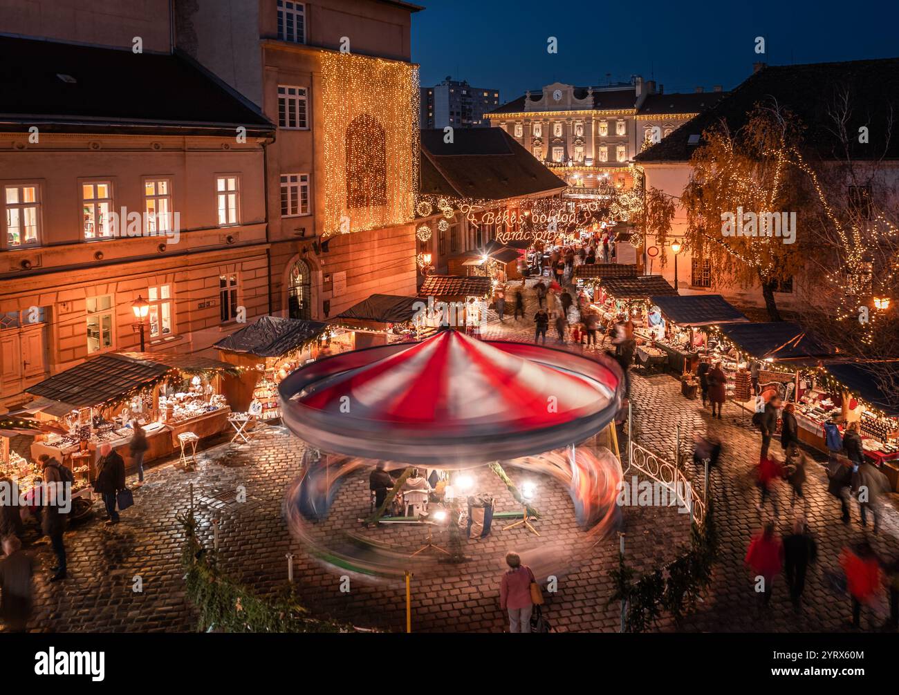 Budapest, Ungheria - Vista aerea del mercato di Natale e della giostra in Piazza Szentlek, Obuda al tramonto. Negozi decorativi illuminati, decorazioni natalizie Foto Stock