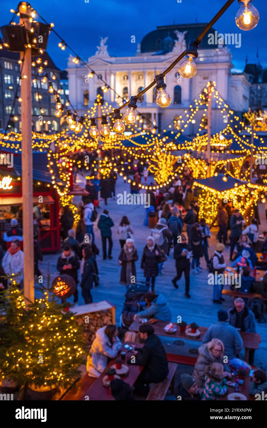 3-12-2024 Zurigo, Svizzera. Persone che visitano i negozi pop-up al mercato di Natale di Sechselautenplatz. Ora blu in tarda serata, luci di Natale. Foto Stock