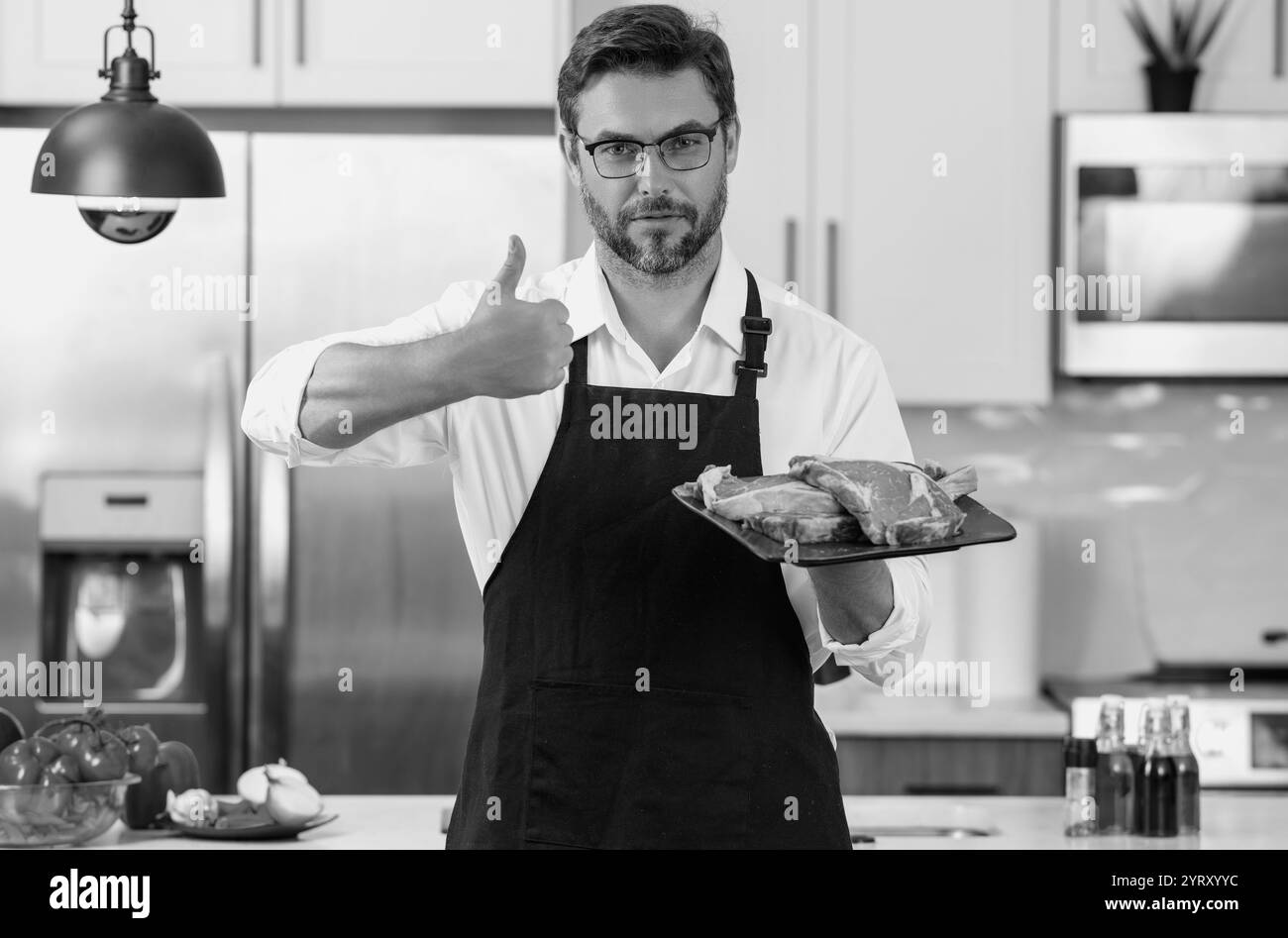 Salute, concetto di proteina naturale. Bell'uomo in cucina cucinando carne di manzo in cucina. Concetto di cibo sano. Dieta sana, proteine di carne. Forchetta di vitello Foto Stock