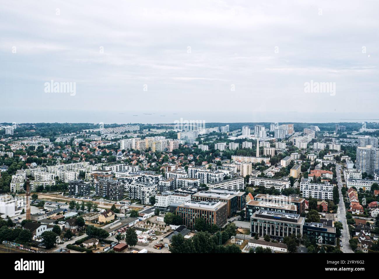 Vista aerea delle aree residenziali e urbane di Danzica che si estendono verso il Mar Baltico. Moderno paesaggio urbano sotto un cielo nuvoloso. Danzica, Polonia - 19 maggio 2024 Foto Stock