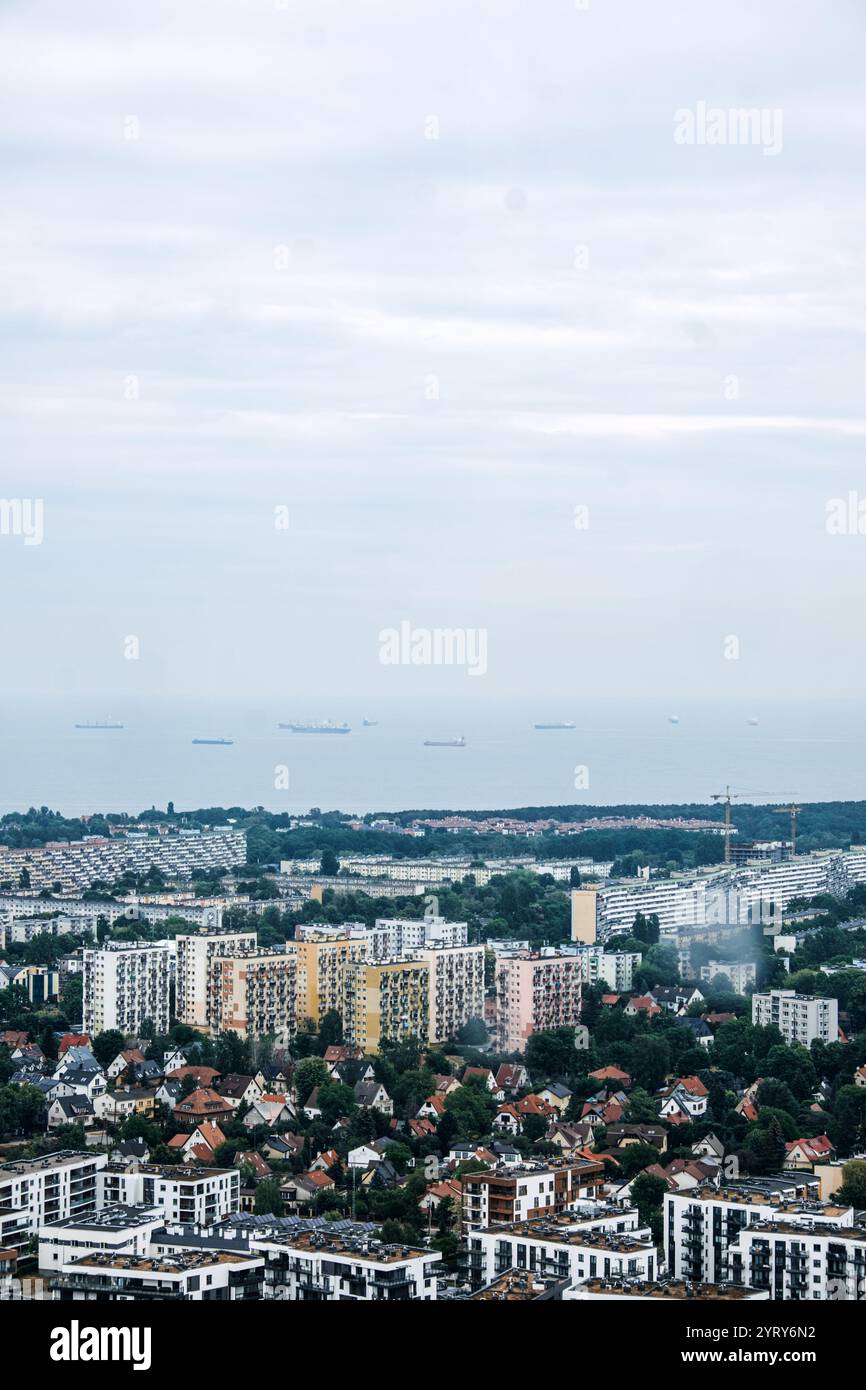Vista aerea delle aree residenziali e urbane di Danzica che si estendono verso il Mar Baltico. Moderno paesaggio urbano sotto un cielo nuvoloso. Danzica, Polonia - 19 maggio 2024 Foto Stock