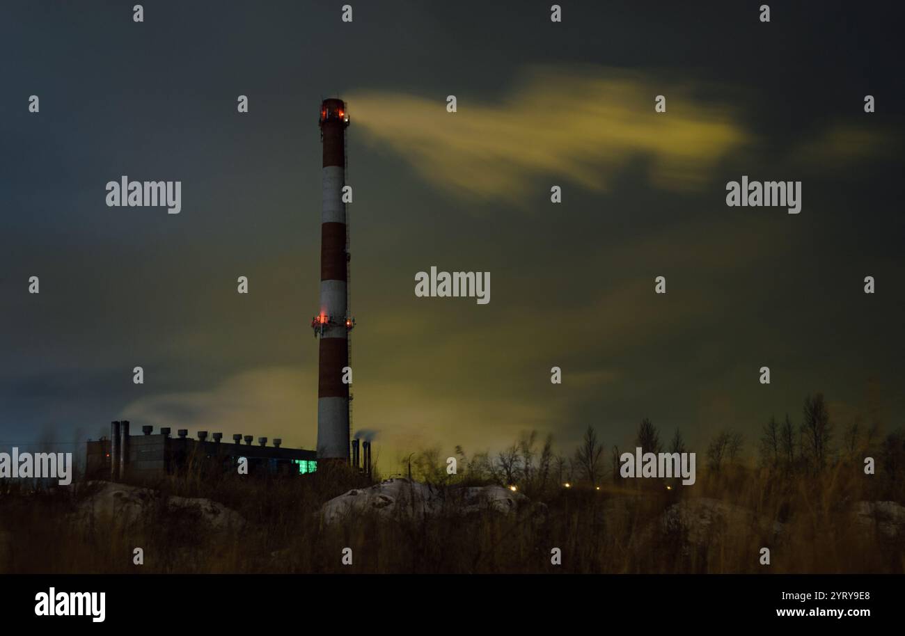 Vista della caldaia con un camino alto e fumo nel bel mezzo della notte Foto Stock