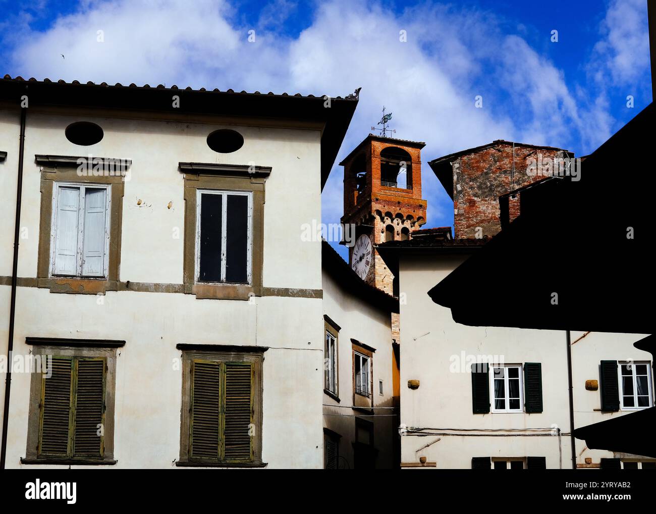 Lucca, splendido vicolo medievale del centro storico con la vecchia Torre dell'ore, un punto di riferimento della città Foto Stock