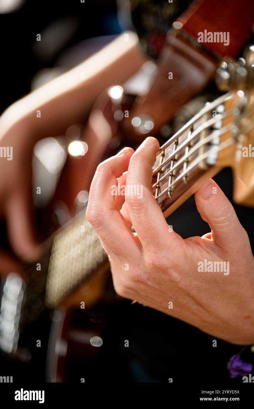Primo piano della mano di un musicista che toglie le corde di una chitarra basso, enfatizzando le prestazioni musicali, la tecnica e la maestria artigianale. Foto Stock