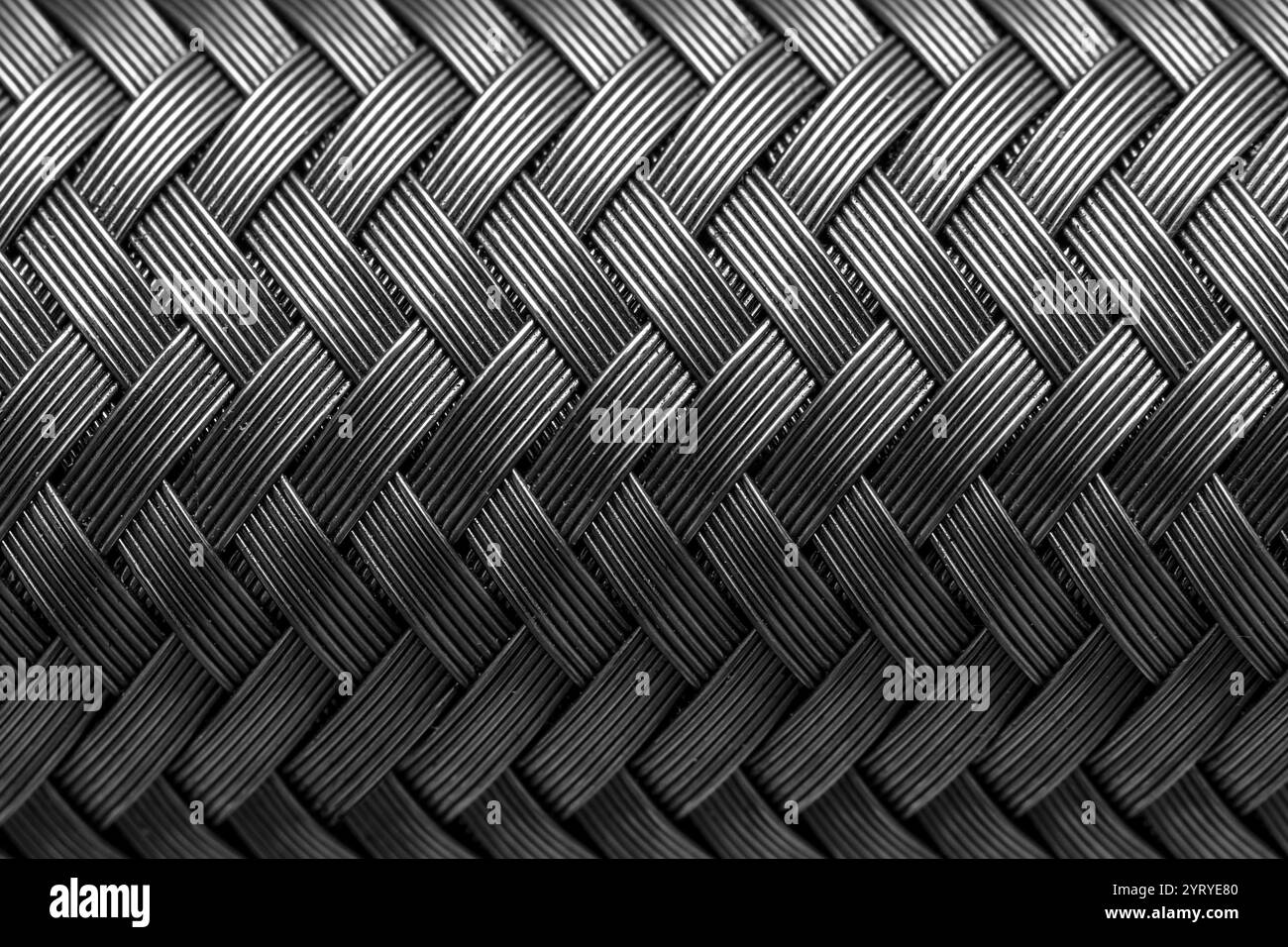Primo piano del tubo flessibile in metallo che mostra un intreccio intricato, evidenziando il design industriale e la resistenza dei materiali Foto Stock