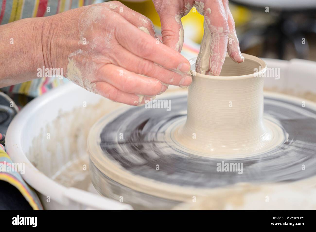 Modellare le mani sull'argilla su una ruota di ceramica, mettendo in risalto l'artigianato tradizionale, l'arte della ceramica e la produzione artigianale di ceramiche. Foto Stock