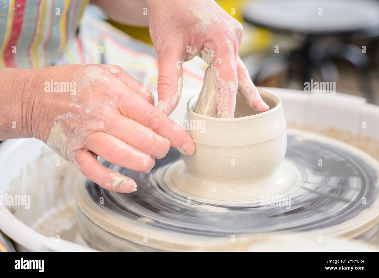 Modellare le mani sull'argilla su una ruota di ceramica, mettendo in risalto l'artigianato tradizionale, l'arte della ceramica e la produzione artigianale di ceramiche. Foto Stock