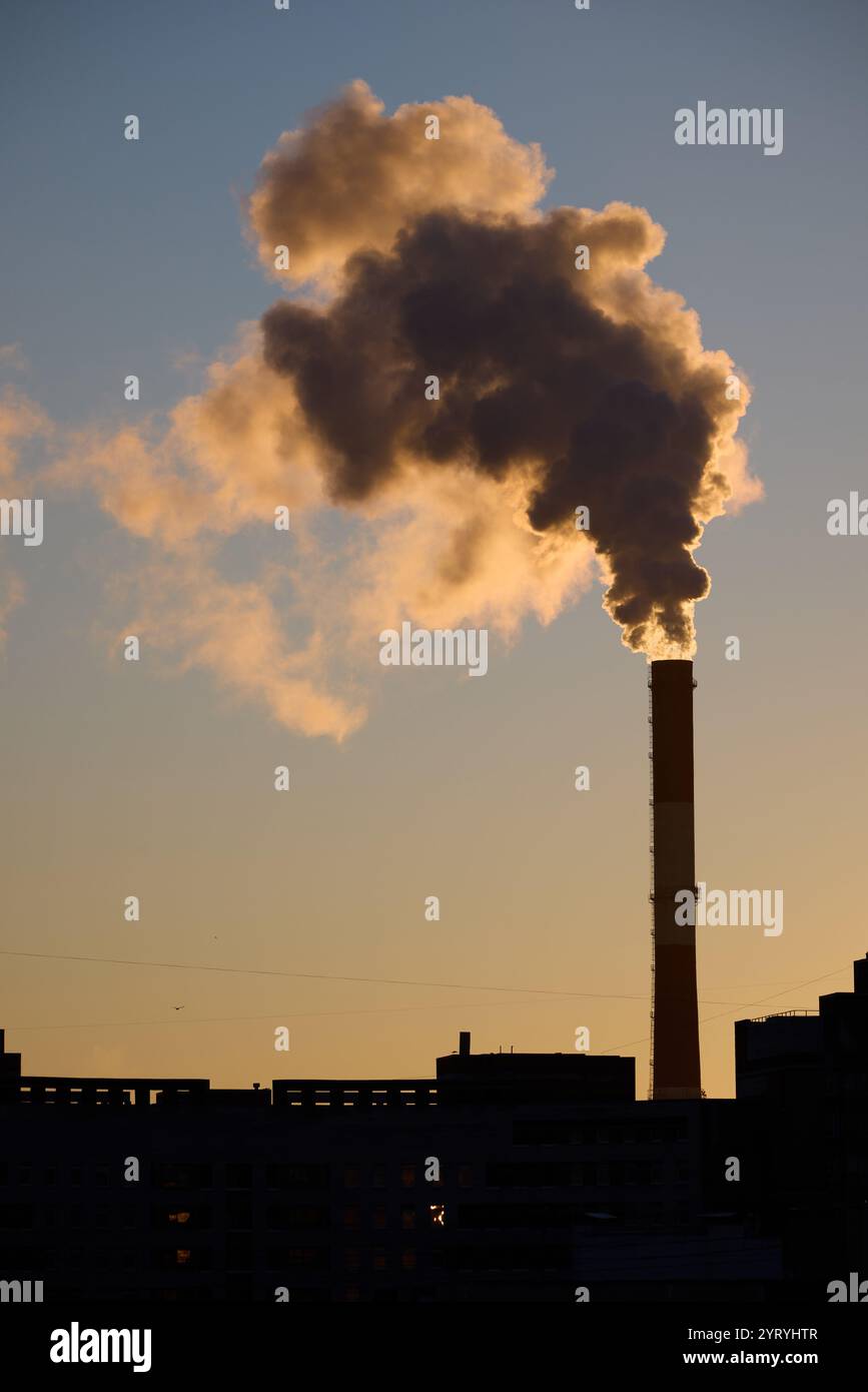 Si vede la suggestiva silhouette di un'alta cisterna che emette grandi nuvole sullo sfondo del tramonto Foto Stock