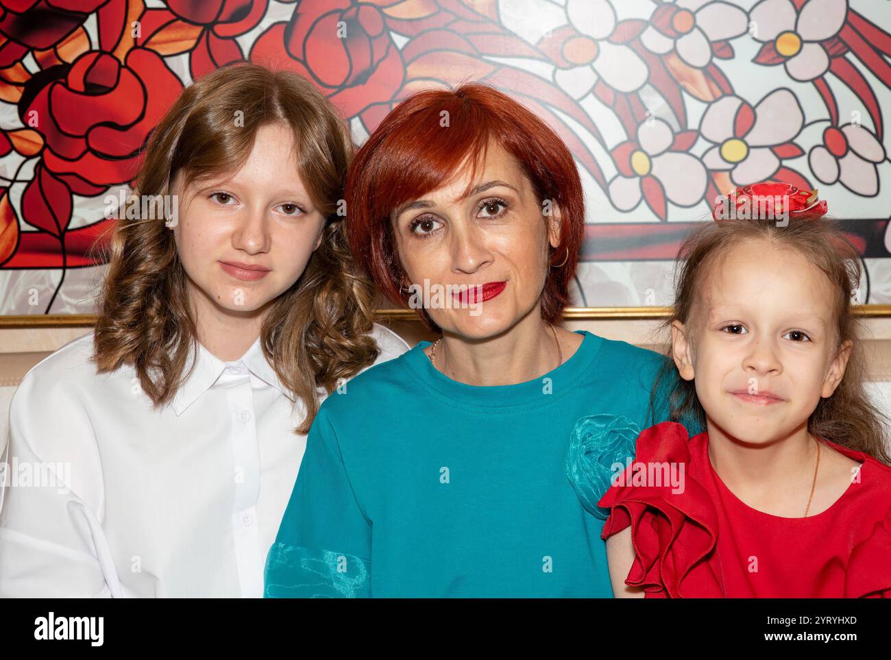 Una madre single con le sue due figlie, un'adolescente di 15 anni e una ragazza di 8 anni, che posa insieme in un ritratto di famiglia. La madre ha i capelli rossi, t Foto Stock