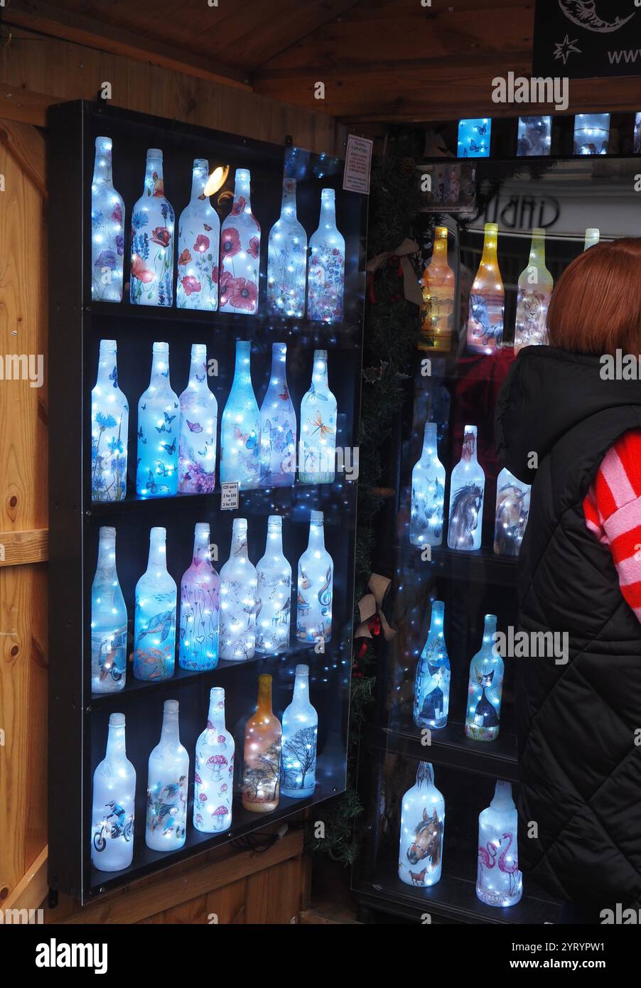 Esposizione illuminata di bottiglie di vetro verniciato al mercatino di Natale di Bath con la possibilità di sfogliare i clienti. Foto Stock