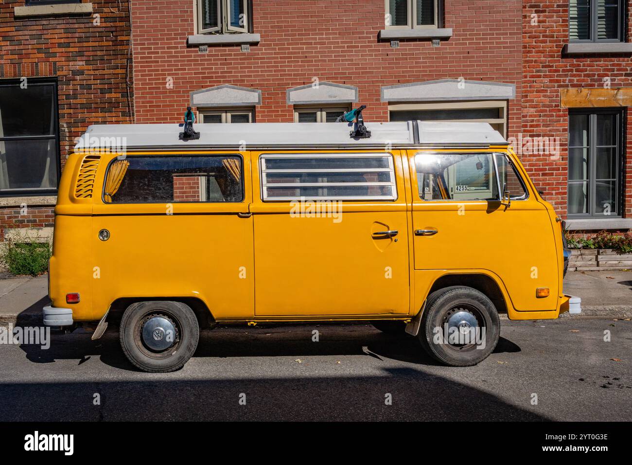 Montreal, QC, Canada-30 settembre 2024: Pulmino con camper VW giallo brillante parcheggiato in strada. Foto Stock