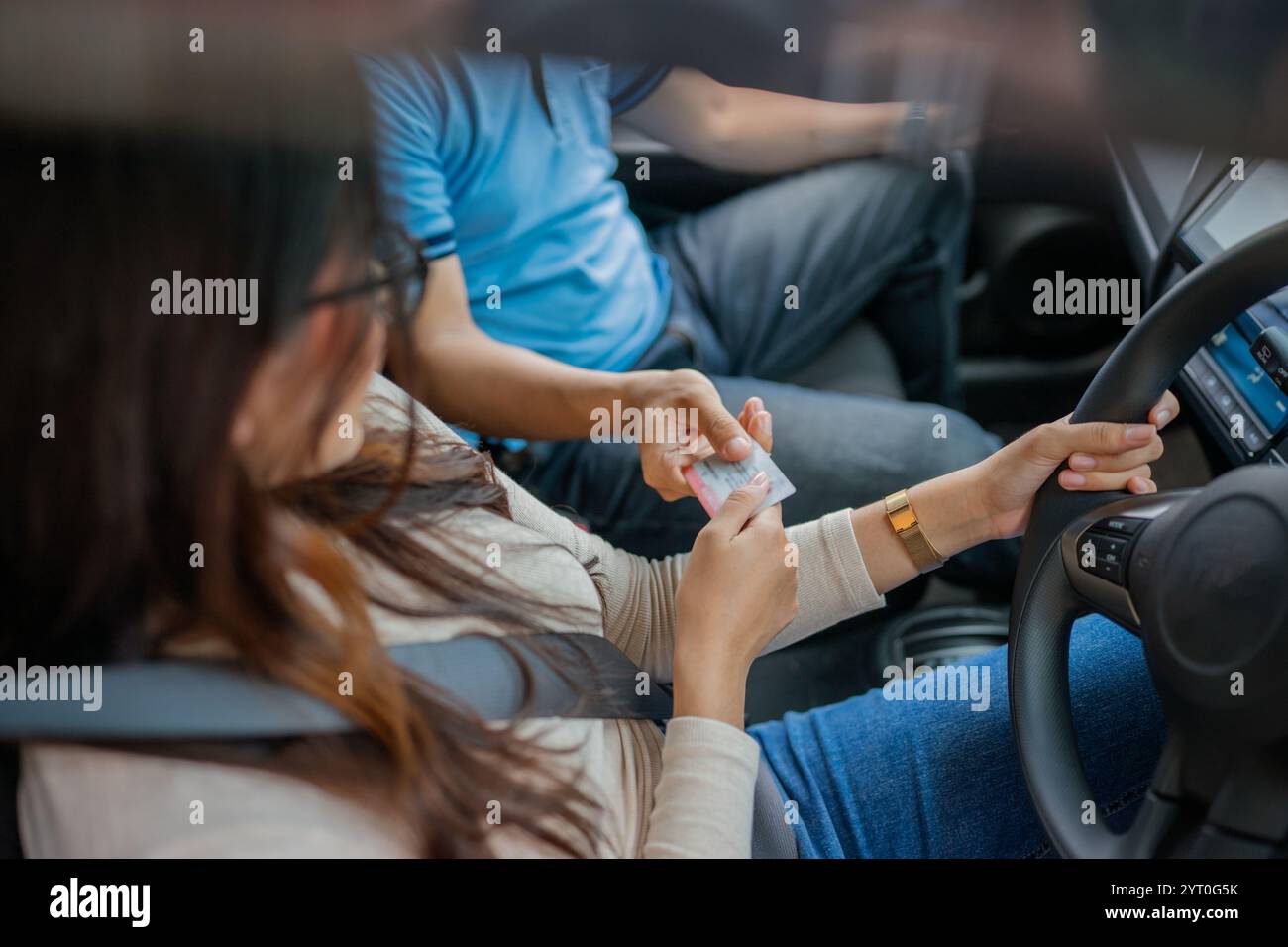 Un conducente e un passeggero impegnati in un'interazione amichevole durante il loro viaggio in auto Foto Stock