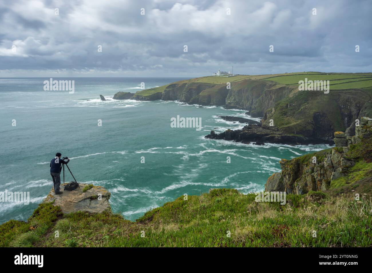 Fotografo che fotografa il faro di Lizard dalle scogliere sopra Housel Bay, Lizard Peninsula, Inghilterra. Autunno (settembre) 2024. Foto Stock