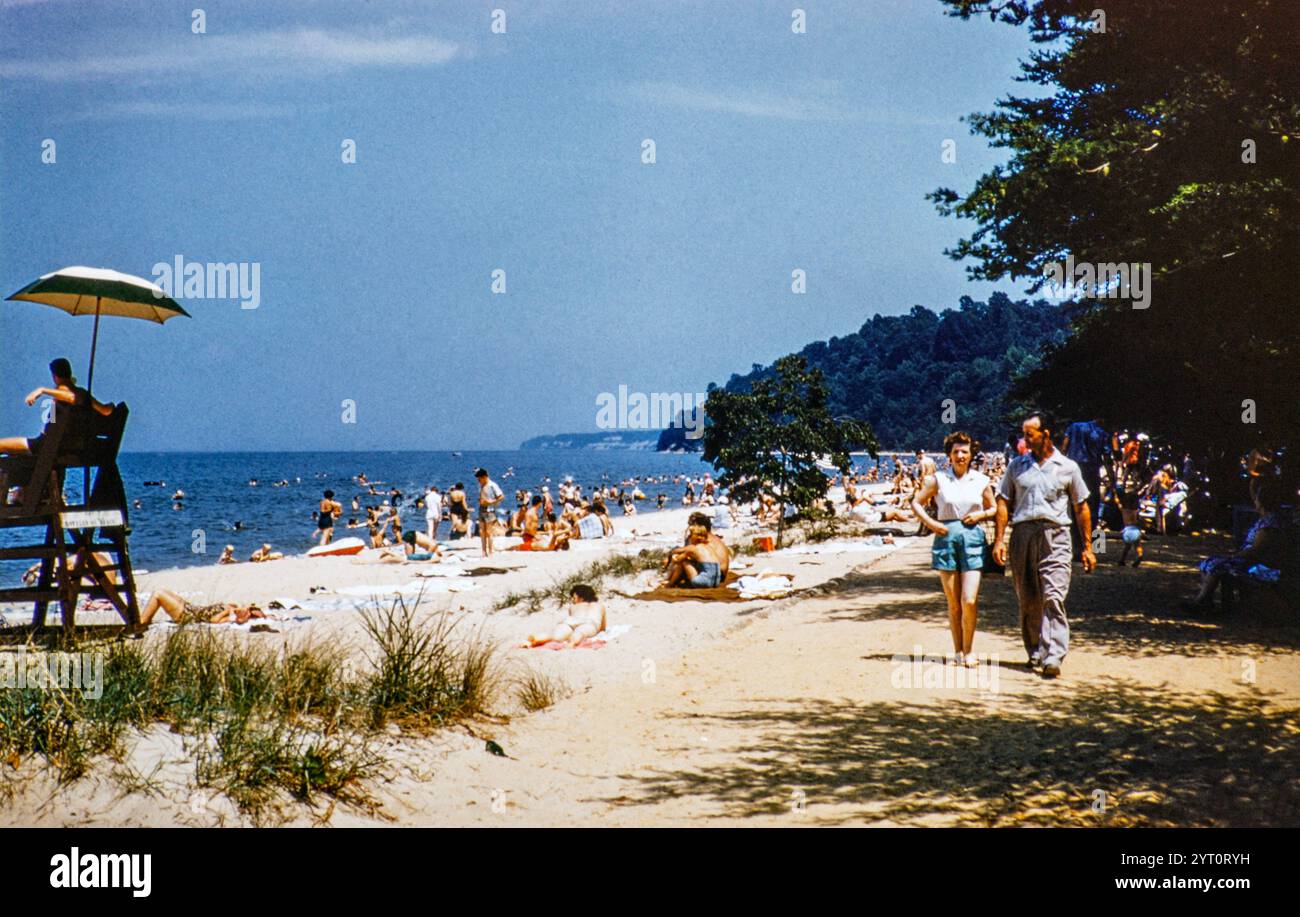Persone che amano il sole estivo sulla spiaggia affollata con bagnino che tiene d'occhio, USA 1953 Foto Stock