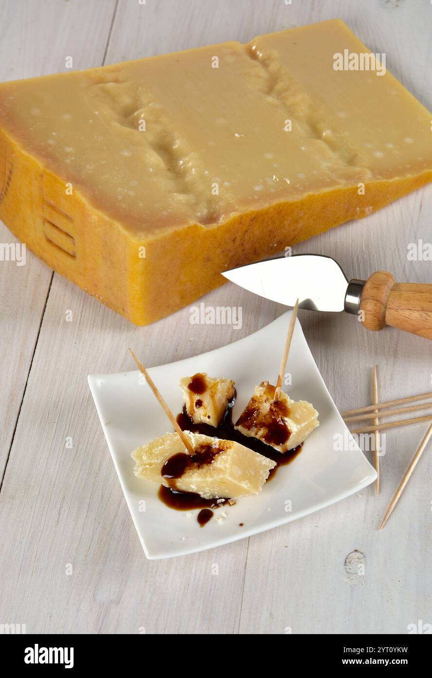 Il Parmigiano Reggiano scaglie con aceto balsamico gocciola su un piattino Foto Stock