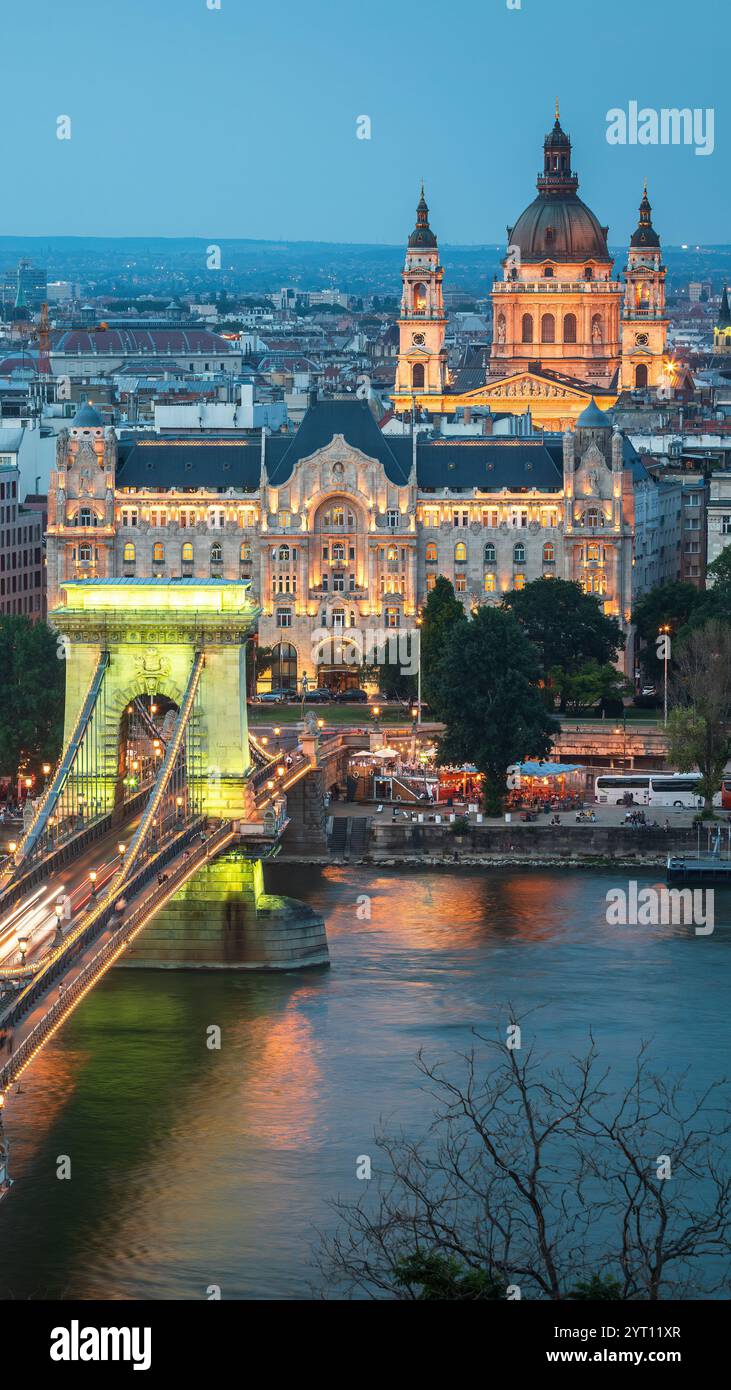 La foto mostra Budapest serale con il Ponte delle catene illuminato e la basilica di Santo Stefano sullo sfondo, mettendo in evidenza il fascino e l'arco della città Foto Stock