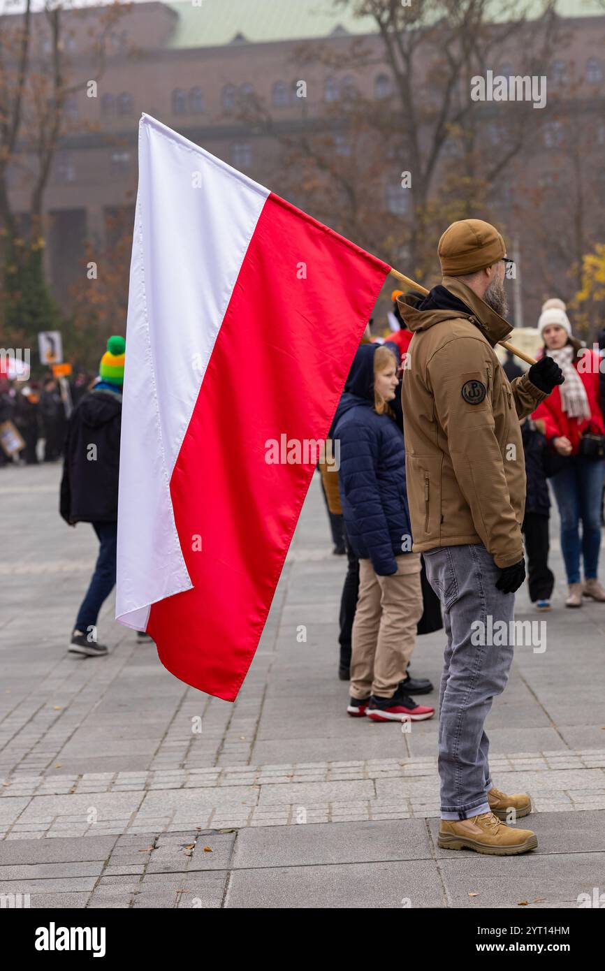 Wroclaw, Polonia - 11 novembre 2024: Uomo con bandiera polacca durante un incontro pubblico in un giorno d'autunno in una piazza della città Foto Stock