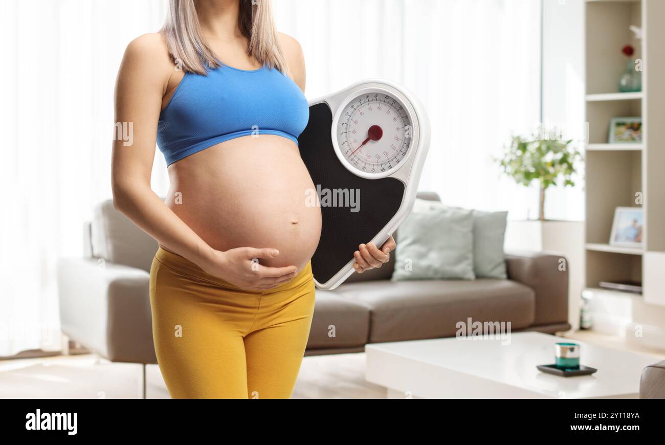 Peso sano durante il concetto di gravidanza, donna con una bilancia in una stanza Foto Stock