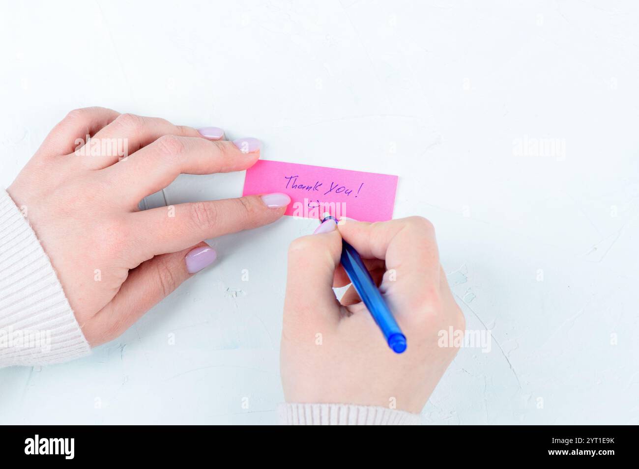 Le mani femminili disegnano un emoji felice sotto l'iscrizione Grazie. Regali concettuali. Foto Stock