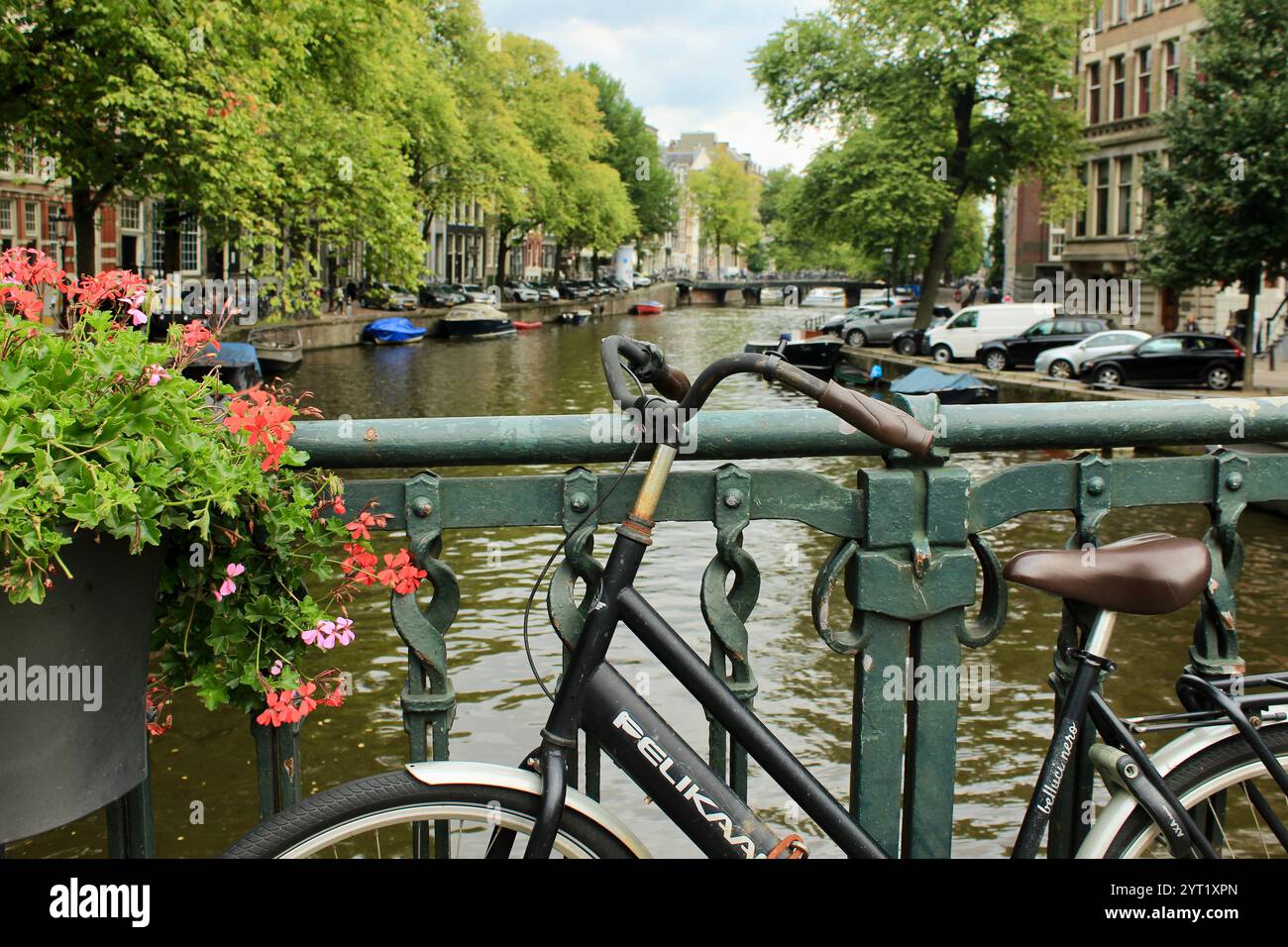 Amsterdam, Paesi Bassi - 8 settembre 2018: Vista panoramica del canale di Amsterdam con bicicletta su un ponte in primo piano e fiori colorati Foto Stock