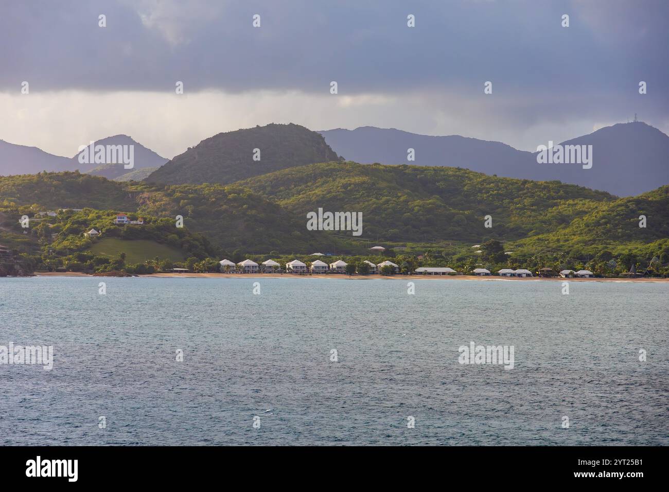 Arrivo in mare ad Antigua Caribbean la mattina presto con ville sulla spiaggia e montagne sullo sfondo Foto Stock