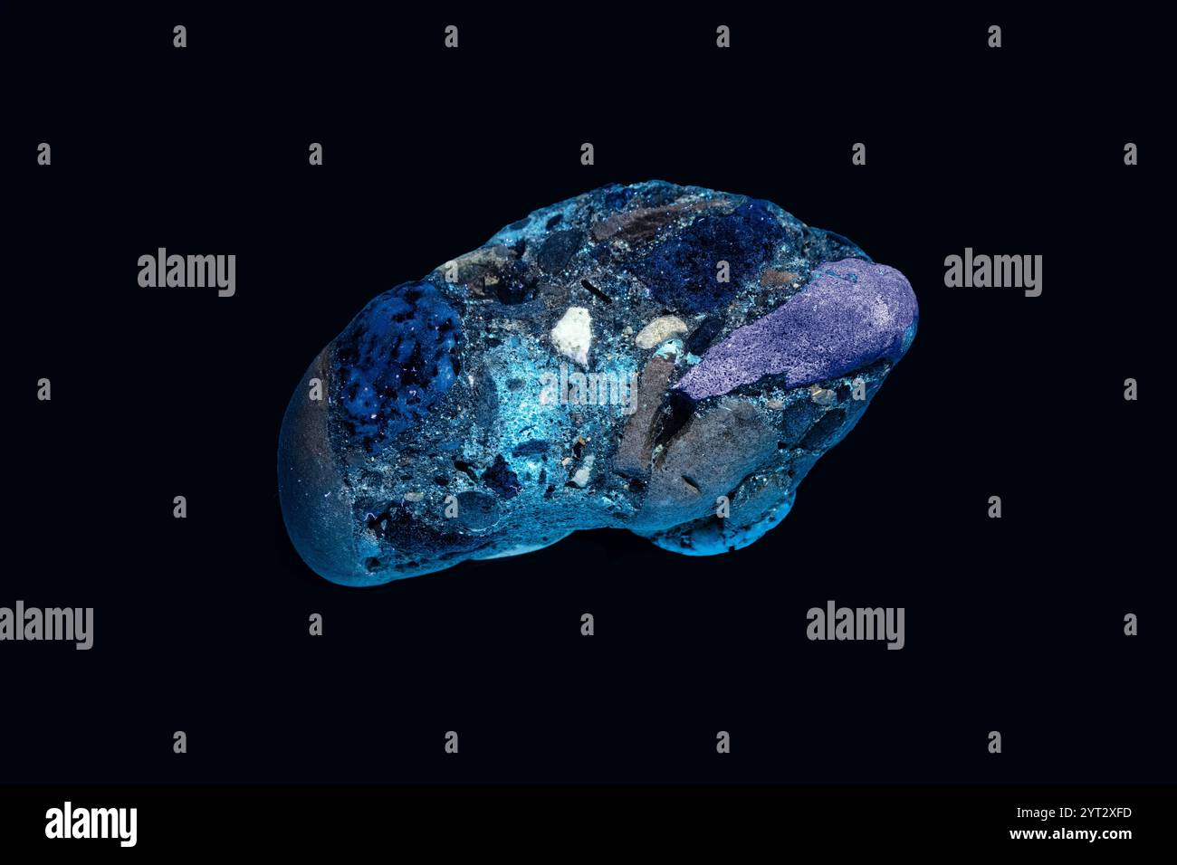 Colori fluorescenti di un conglomerato con luce UV inferiore a 365 nanometri. Isolato su sfondo scuro. Si veda la stessa roccia sotto la luce normale ID 2YT1H66 Foto Stock