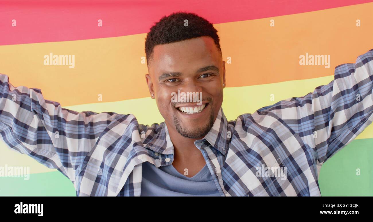 Ritratto di un uomo afroamericano felice con bandiera arcobaleno lgbt, al rallentatore Foto Stock