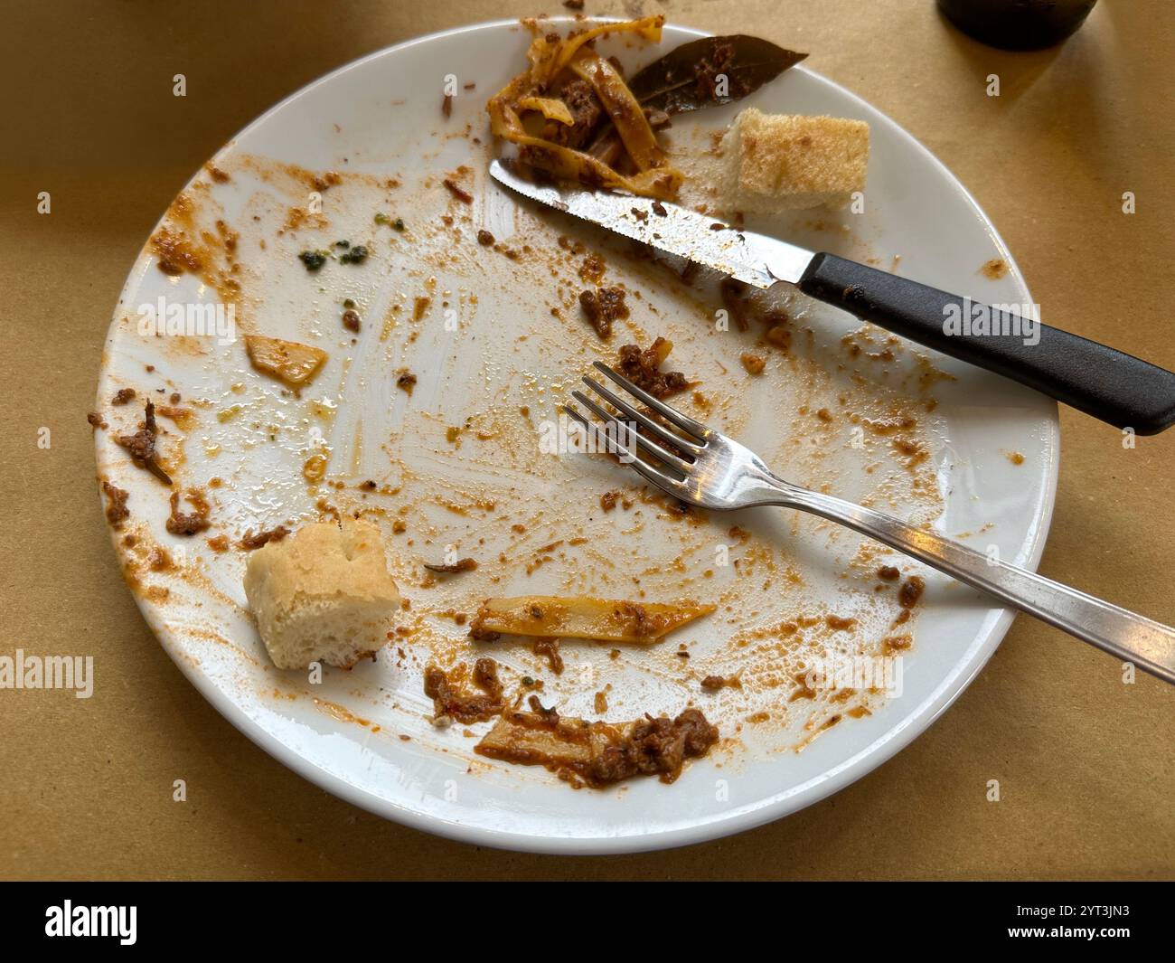 I resti dopo aver mangiato un piatto di pasta ragù di cinghiale e un pasto di pane sono mostrati su un tavolo in un ristorante in Italia. - Immagine stock catturata con smartphone