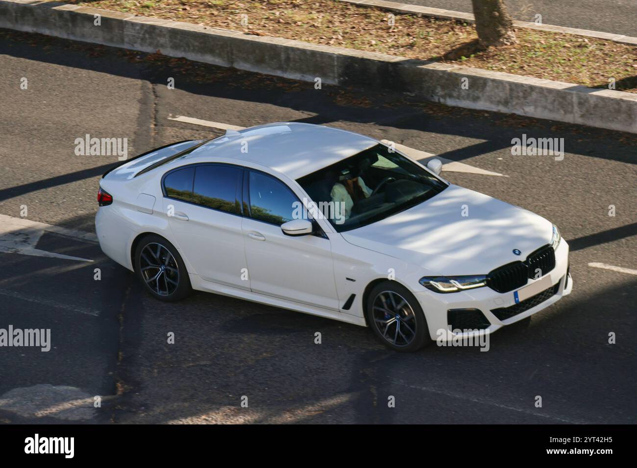 una bmw bianca viene guidata su una strada asfaltata da un pilota professionista in una giornata di sole Foto Stock